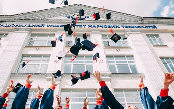 group of fresh graduates students throwing their academic hat in the air
